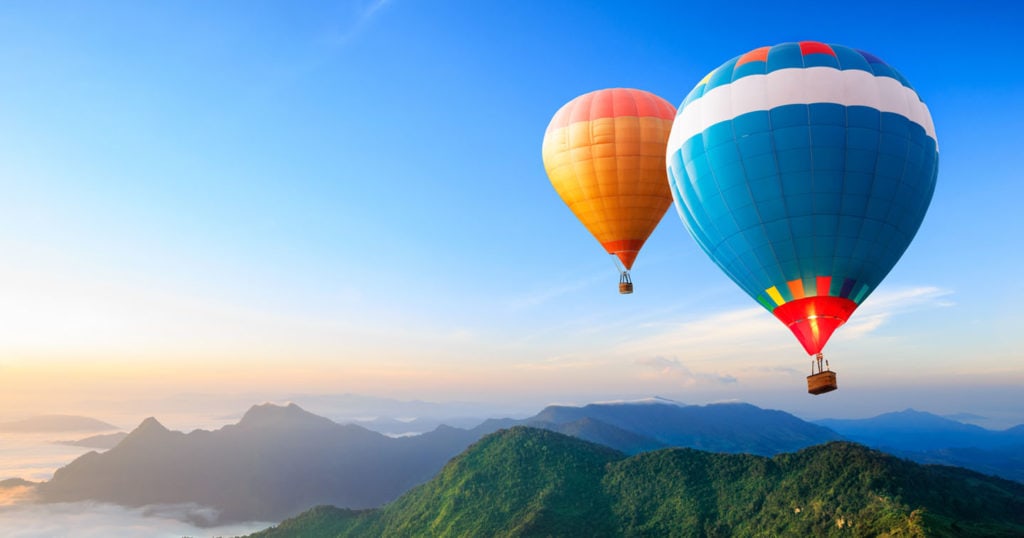 Hot air balloons floating above mountains.